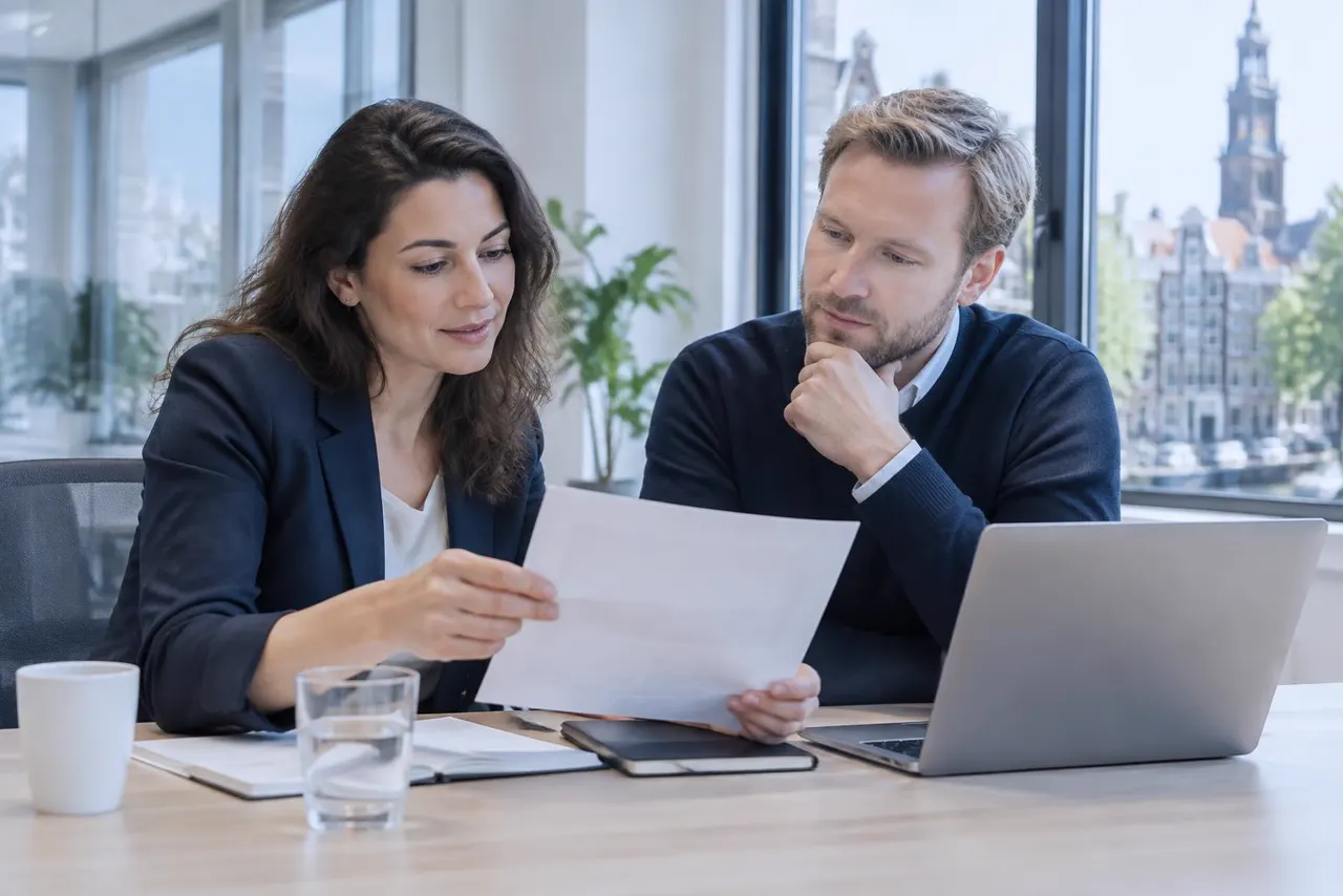 Two colleagues reviewing a document together at a meeting table, illustrating human oversight